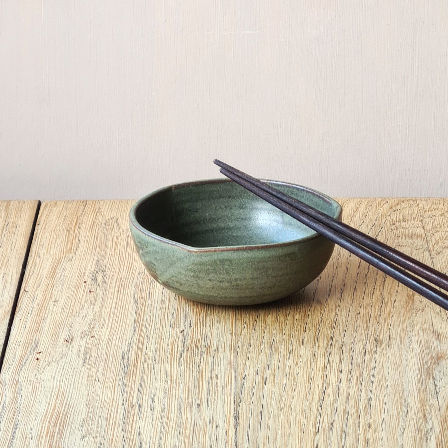 bol vert sauge avec baguettes japonaises posées sur la lèvre
