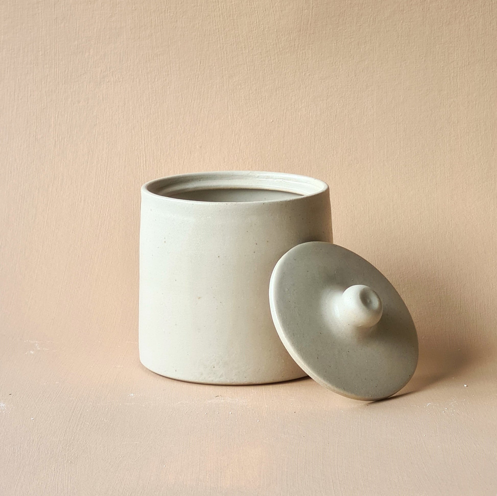 boîte blanche avec couvercle posé en appui. couvercle à bouton.